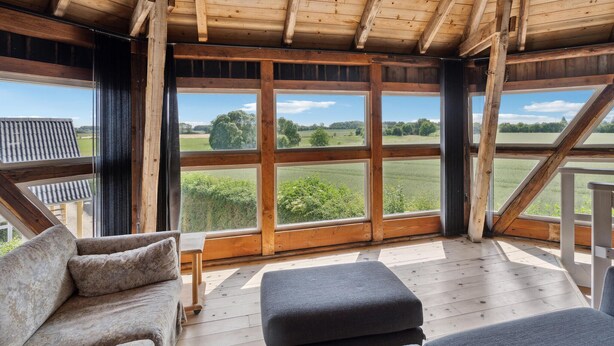 A wooden-paneled room with large windows overlooking a green landscape. - 4 bedroom nice home in Nyborg (Nyborg)