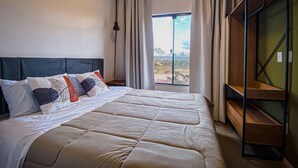 Een moderne hotelkamer met een groot bed, uitzicht op de omgeving en een inbouwkleerkast.