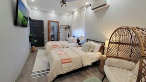 A bedroom with two beds, a large window with curtains, a ceiling fan, and a wicker chair. - Villa on the Rock ~ Luxury vacation rental near beach with Roof top lounge area (Trelawny)