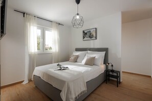 A bedroom with a bed, a bedside table, a lamp, a window with curtains, and a geometric pendant light. - NEW villa with pool for 4 persons near Labin, Istria (Labin)