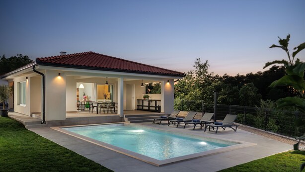 Una casa moderna con piscina, un patio cubierto y un comedor.
