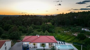Una casa con techo de tejas rojas, piscina y césped cuidado.