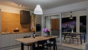 Una cocina moderna con encimera de madera, horno empotrado y zona de comedor con mesa y sillas.