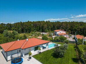 A residential area with a house featuring a red-tiled roof, a swimming pool, and a trampoline. - NEW villa with pool for 4 persons near Labin, Istria (Labin)