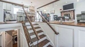 Et moderne interiør med trappe, køkken og opholdsstue med pejs.