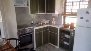 A compact kitchen with a stove, oven, sink, and green cabinets. - Henrietta's Seaview Studio (Gros Islet)