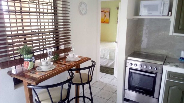 A kitchen with a stove, microwave, and dining area with a table and chairs. - Henrietta's Seaview Studio (Gros Islet)