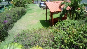 A well-maintained garden with a gazebo, a car parked in the background, and a variety of plants and shrubs. - Henrietta's Seaview Studio (Gros Islet)