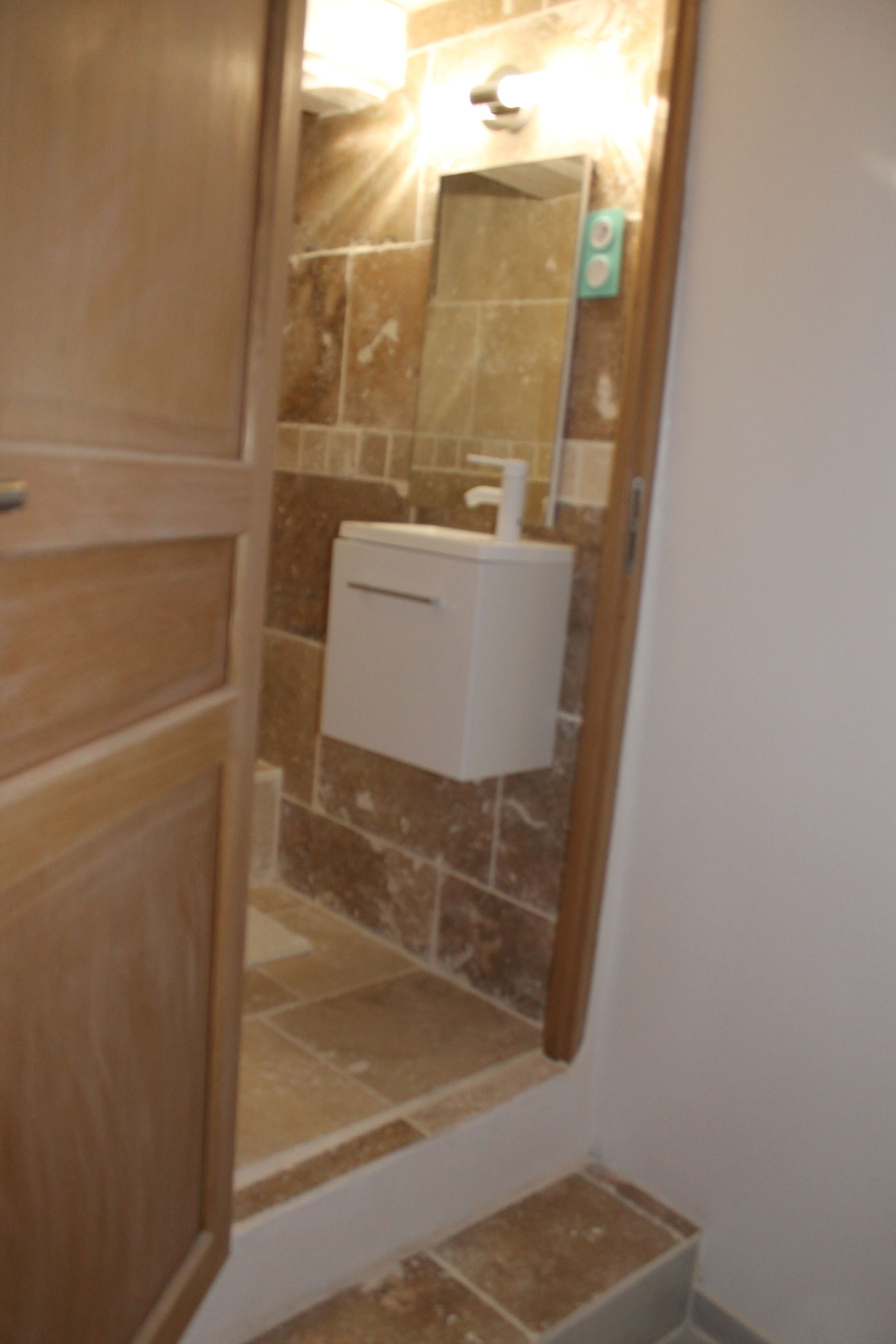 A bathroom with a toilet, sink, and mirror.