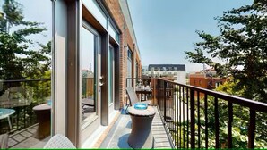 A balcony with a trash bin, a table, and chairs, overlooking a cityscape. - 2 bed/2 bath Condo - Less than 1 Mile to Broadway! (Nashville)