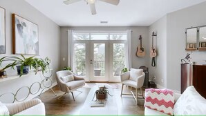 A living room with a sofa, chairs, a coffee table, and a balcony with a view. - 2 bed/2 bath Condo - Less than 1 Mile to Broadway! (Nashville)