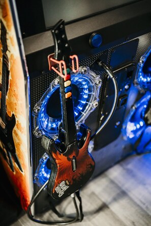Close-up van een gitaar met een transparante pickguard en blauwe LED-verlichting, bevestigd aan een statief.