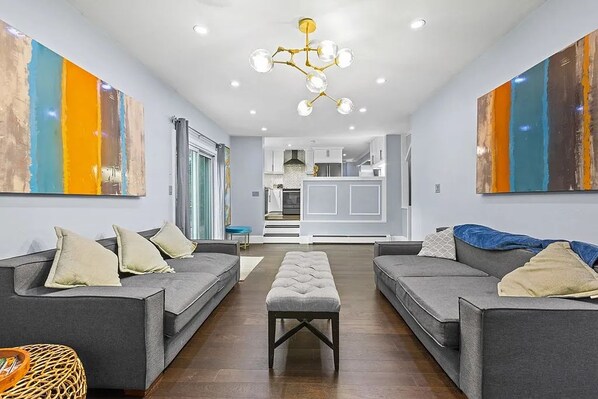 A modern living room with grey sofas, a central ottoman, and abstract art on the walls.