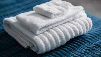 A neatly folded white towel on a blue quilted bedspread.