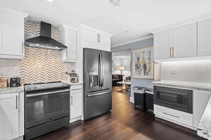 A modern kitchen with white cabinetry, a stainless steel range, a built-in oven, and a microwave.