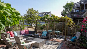 Eine Terrasse mit Gartenmöbeln, einer Feuerstelle und einer Pergola mit Kletterpflanzen.