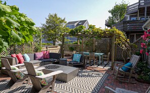 A patio with outdoor furniture, a fire pit, and a pergola with climbing plants.