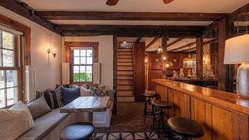 A cozy interior with a wooden bar, seating area, and a staircase leading to an upper level.