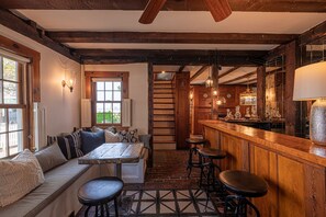 A cozy interior with a wooden bar, seating area, and a staircase leading to an upper level.