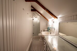 A bathroom with a tiled floor, a toilet, a sink, and a shower area.