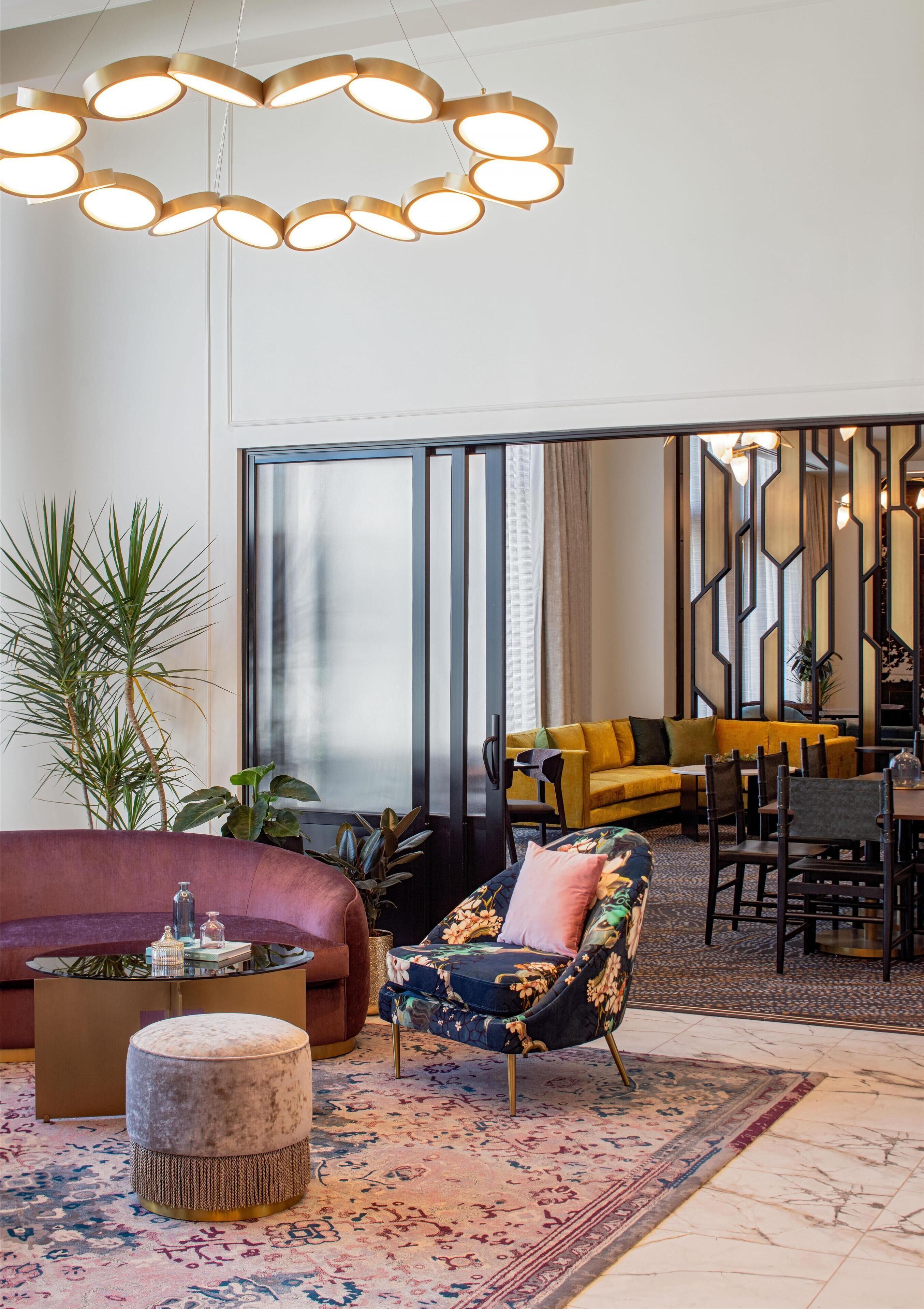 Una sala moderna con sofá, sillón, banqueta y un comedor con sillas y una mesa.