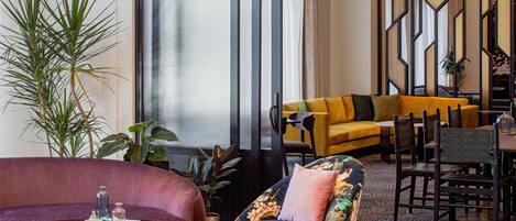 Una sala moderna con sofá, sillón, banqueta y un comedor con sillas y una mesa.