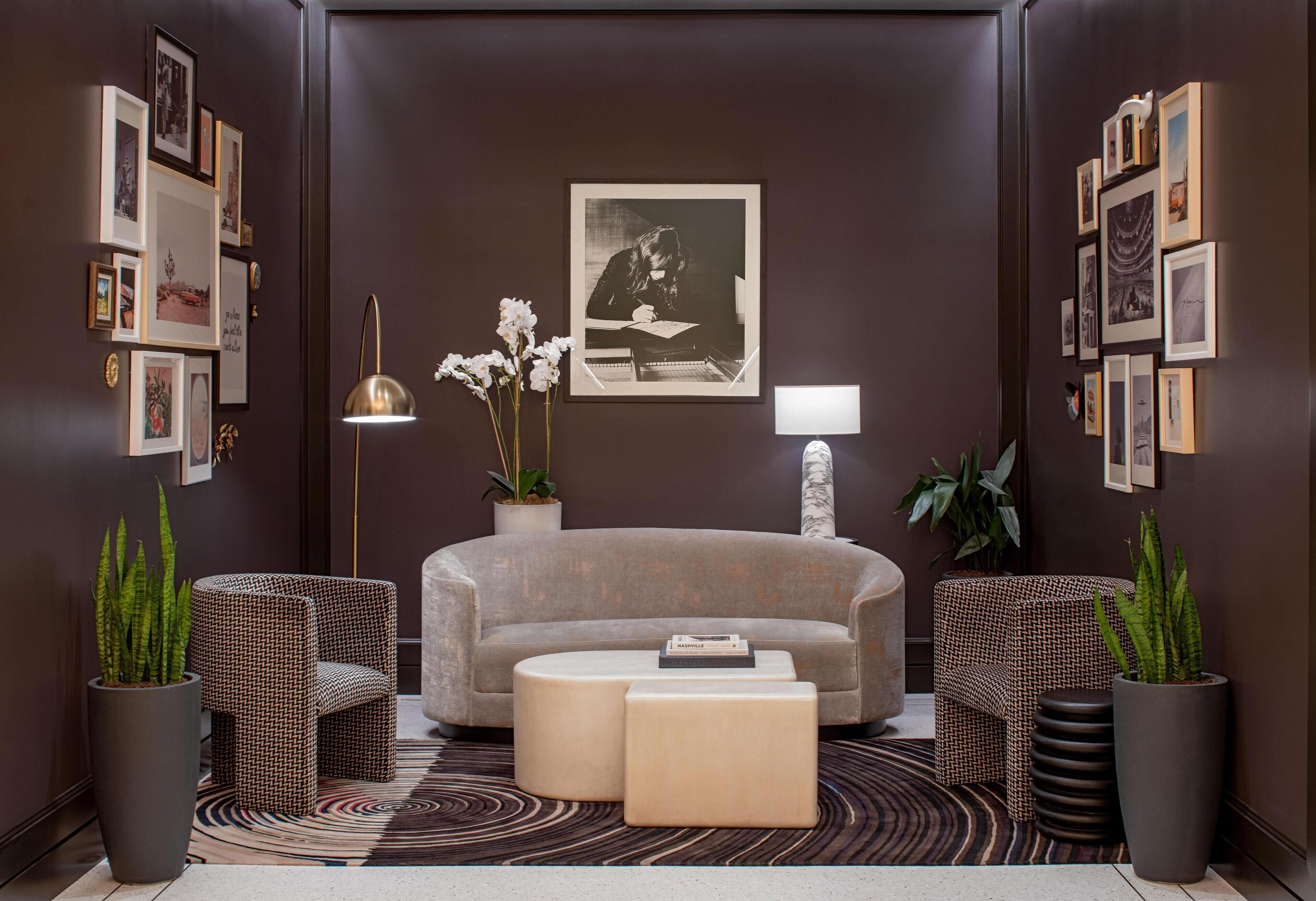 A modern living room with a grey sofa, two patterned armchairs, a coffee table, and a patterned rug.