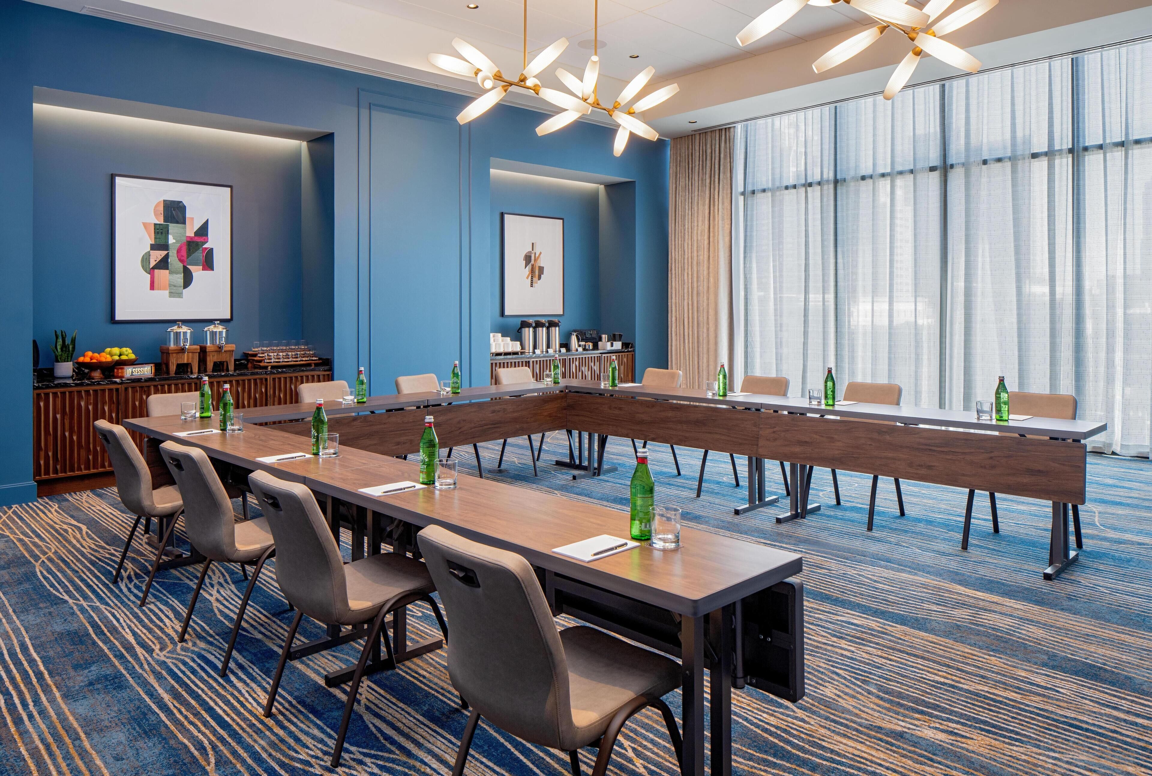 Un salón de conferencias con una larga mesa, sillas y una zona de bufé con comida y bebidas.