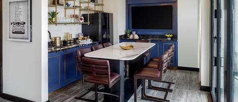 Una cocina moderna con una isla de mármol, armarios azules y un televisor grande.