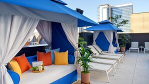 A rooftop lounge with a blue sofa, white and blue canopies, and white lounge chairs. - Tempo By Hilton Nashville Downtown (Nashville)