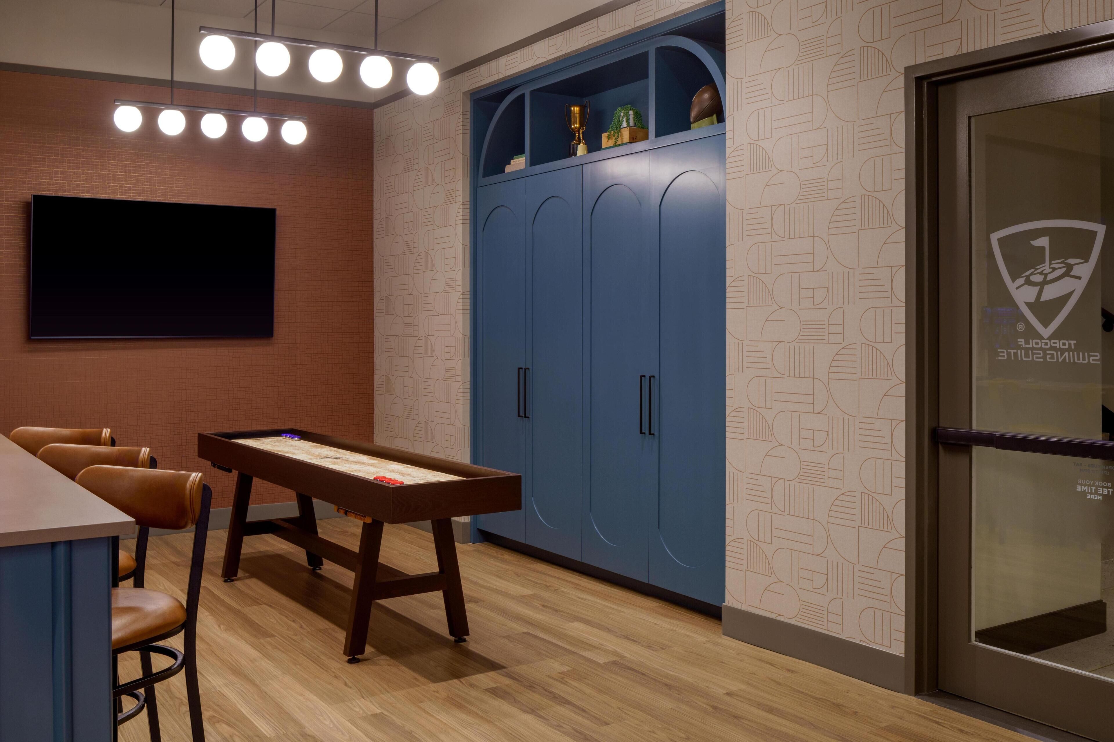 A room with a pool table, bar area, and blue lockers.