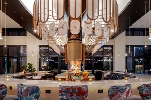 A modern bar area with a central column, bar stools, and a variety of bottles and glasses. - Tempo By Hilton Nashville Downtown (Nashville)