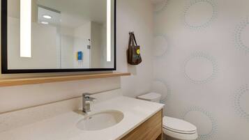 A bathroom with a large mirror, a sink, a toilet, and a wall with a circular pattern.