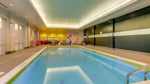 Une piscine intérieure avec des lignes de démarcation bien visibles, un panneau de sécurité et un espace détente avec des chaises.