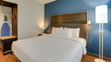 Quarto de hotel com uma cama grande, mesa de cabeceira, espelho, porta-toalhas na parede e abajur.
