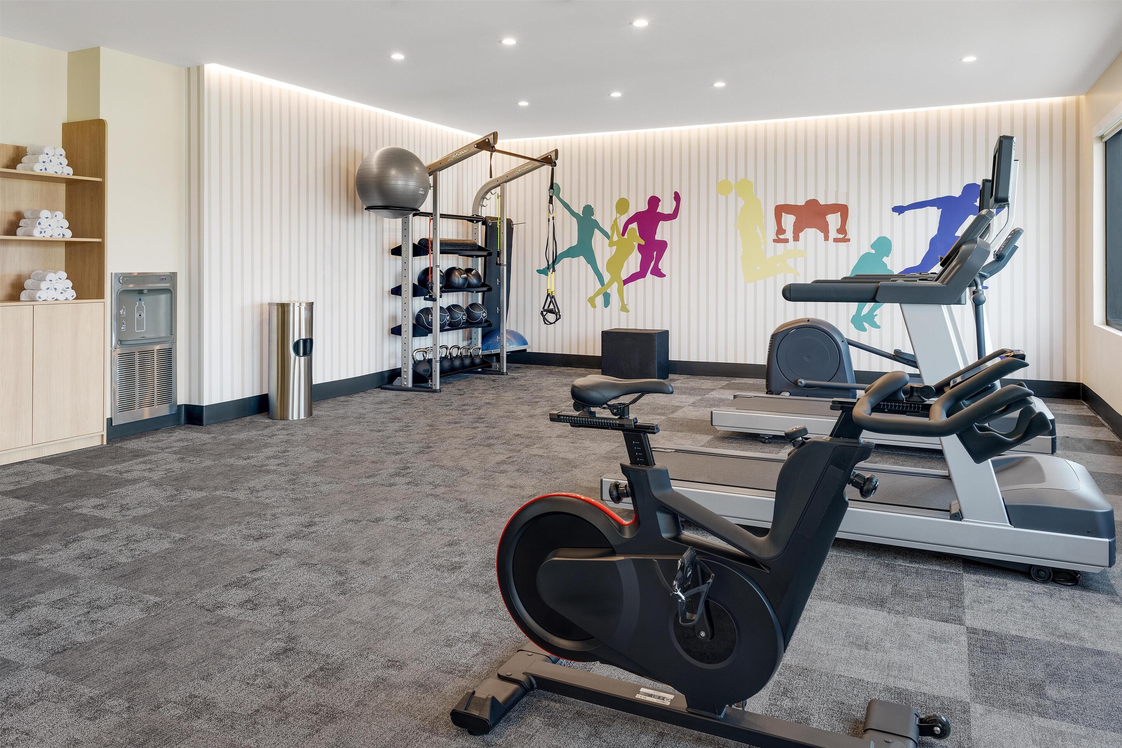 Une salle de sport équipée d’appareils de cardio, de machines de musculation et d’un distributeur d’eau.