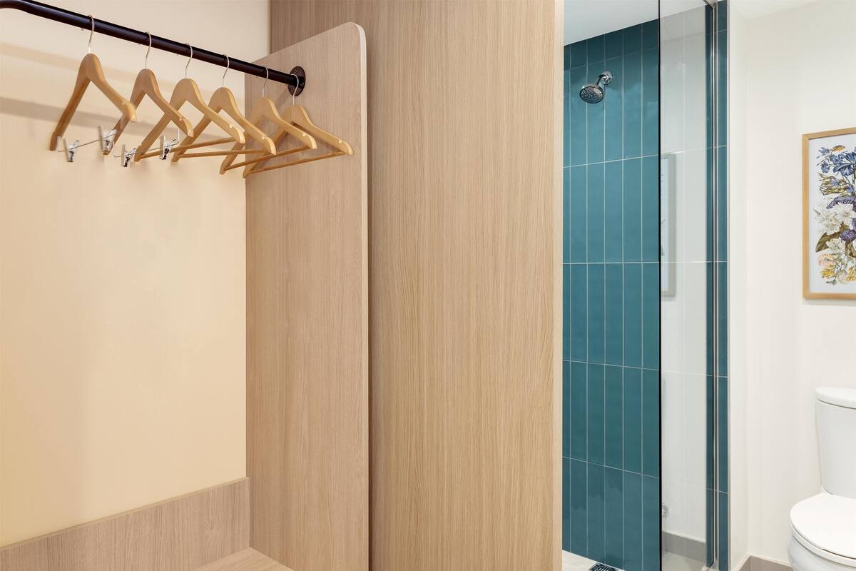 Ein Badezimmer mit Holzhandtuchhalter, Duschbereich und Toilette.