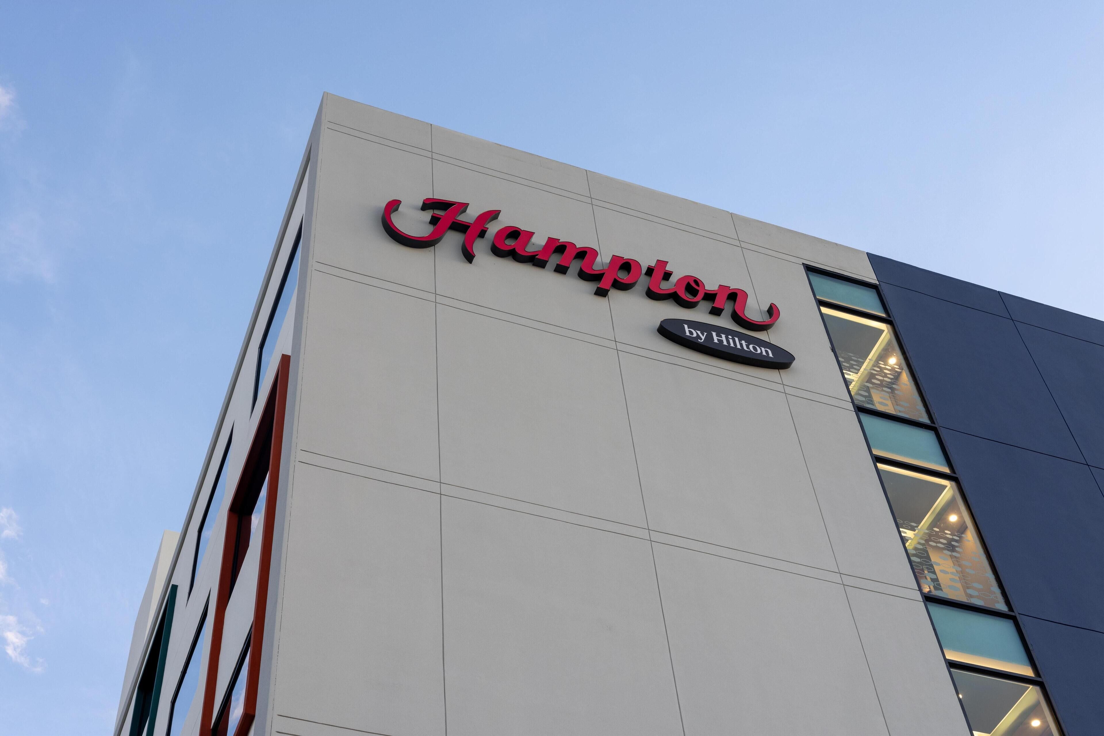 Een gebouw met de tekst 'Hampton by Hilton', wat aangeeft dat het een Hilton hotel is.