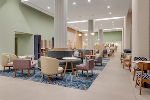 Eine geräumige Lobby mit modernen Sitzgelegenheiten, einem runden Tisch in der Mitte und einem gut einsehbaren Empfangsbereich.