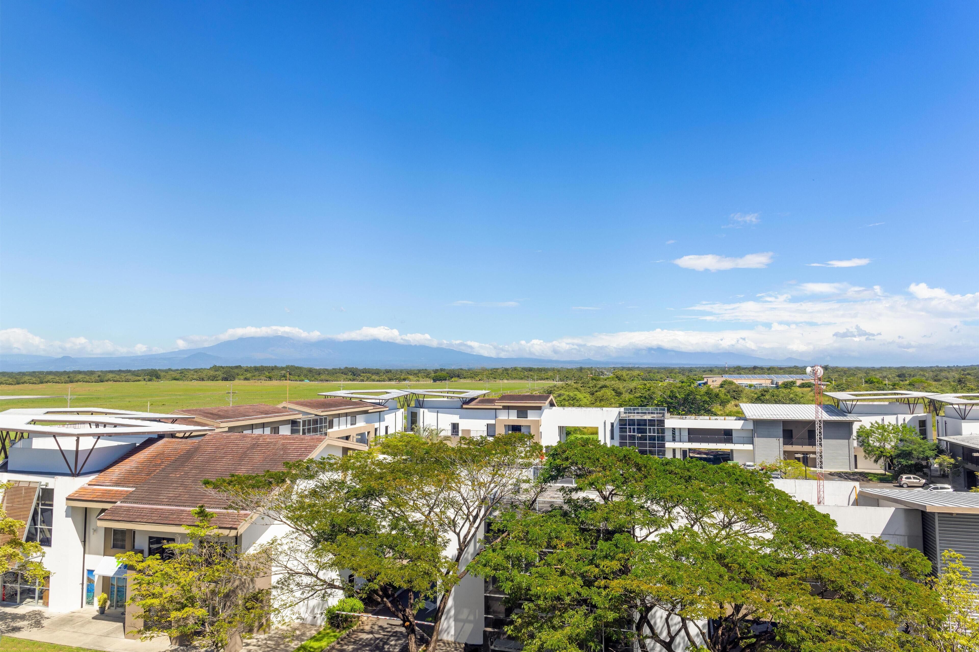 A residential area with modern houses, a clear blue sky, and distant mountains.