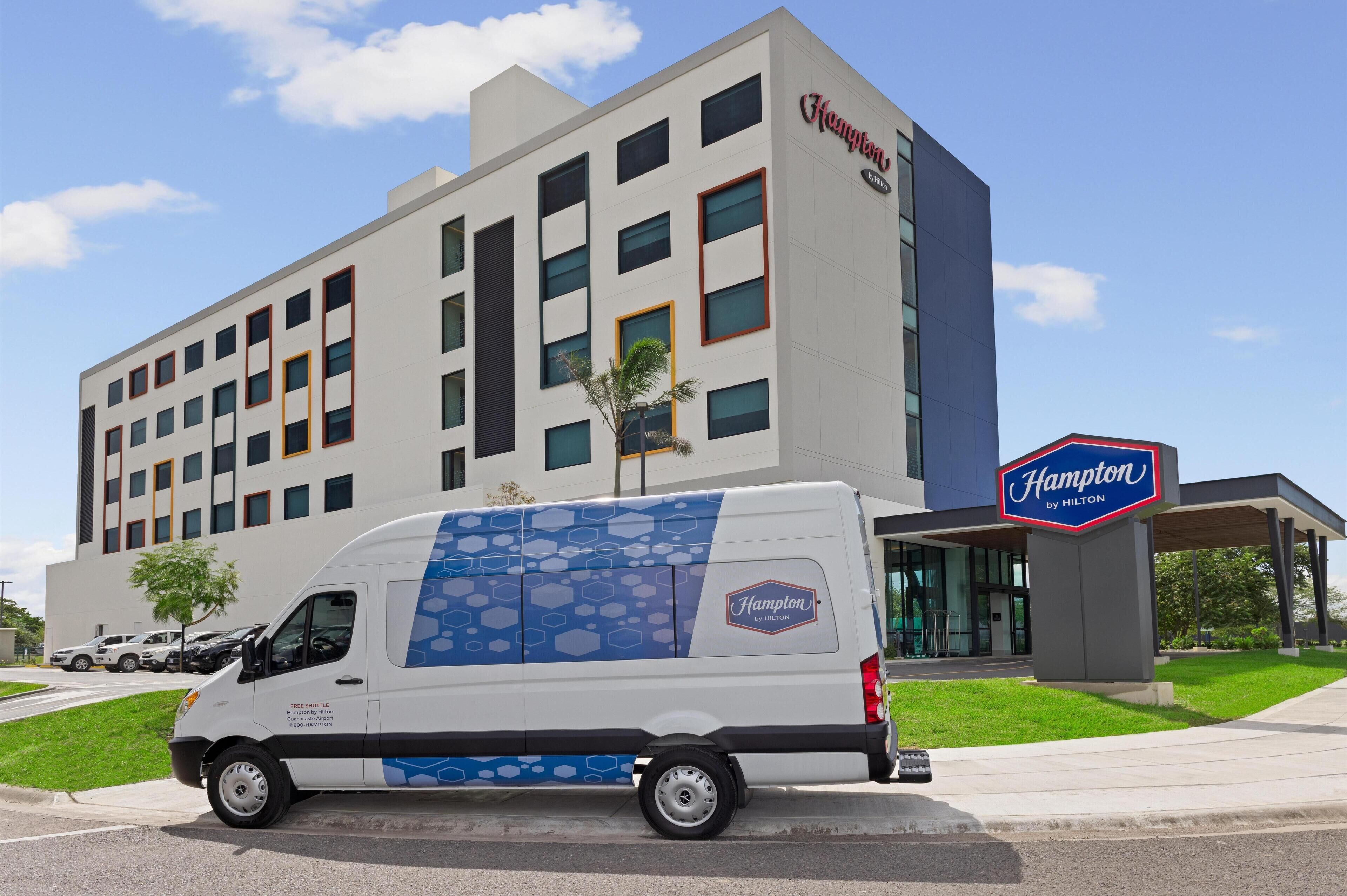 Un hotel Hampton by Hilton con fachada blanca, múltiples ventanas y un letrero que indica la marca.