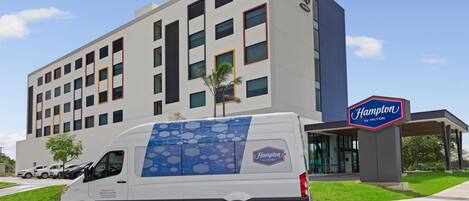 Un hotel Hampton by Hilton con fachada blanca, múltiples ventanas y un letrero que indica la marca.