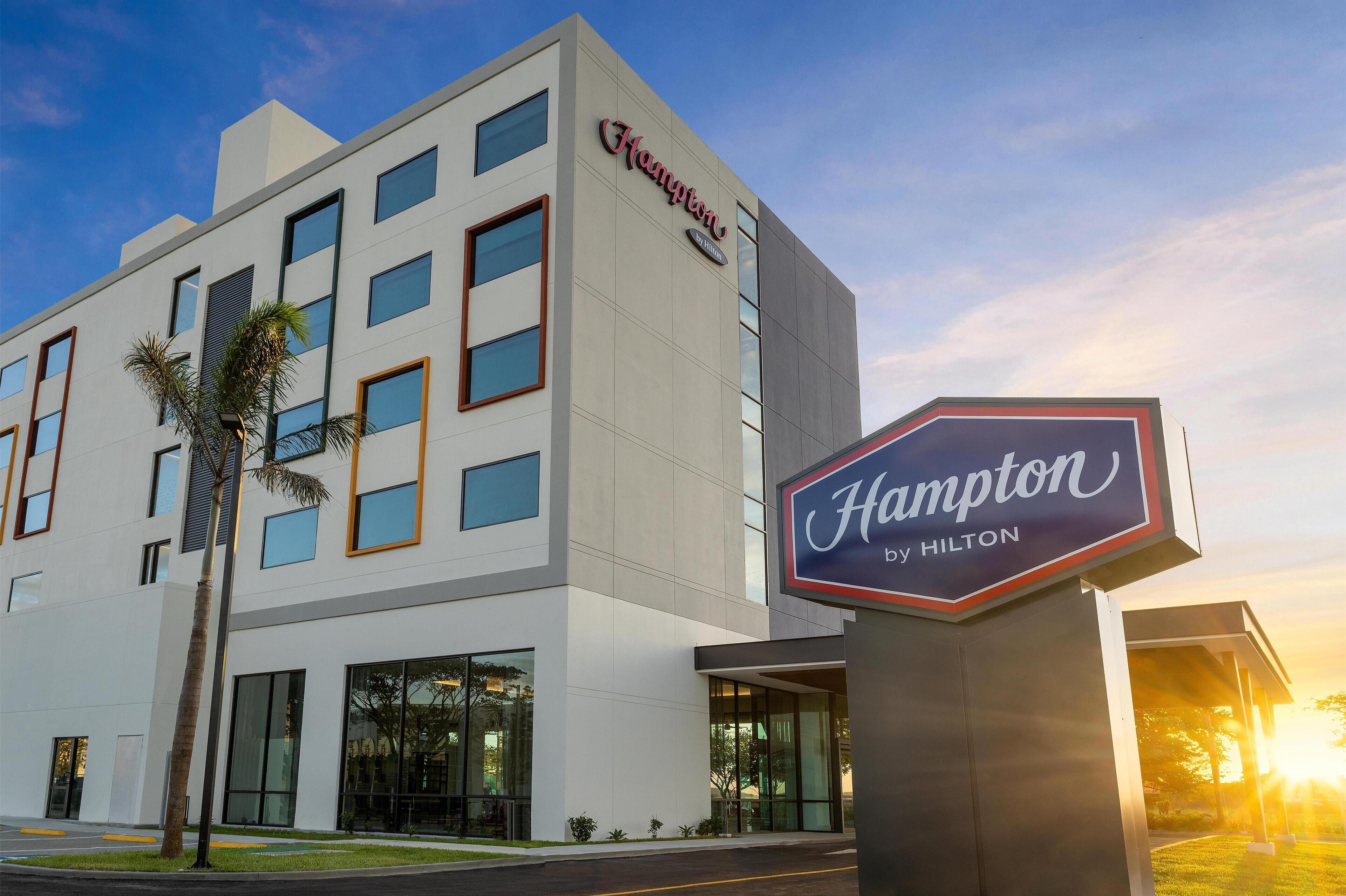 A Hampton by Hilton hotel building with a modern design, large windows, and a prominent sign.