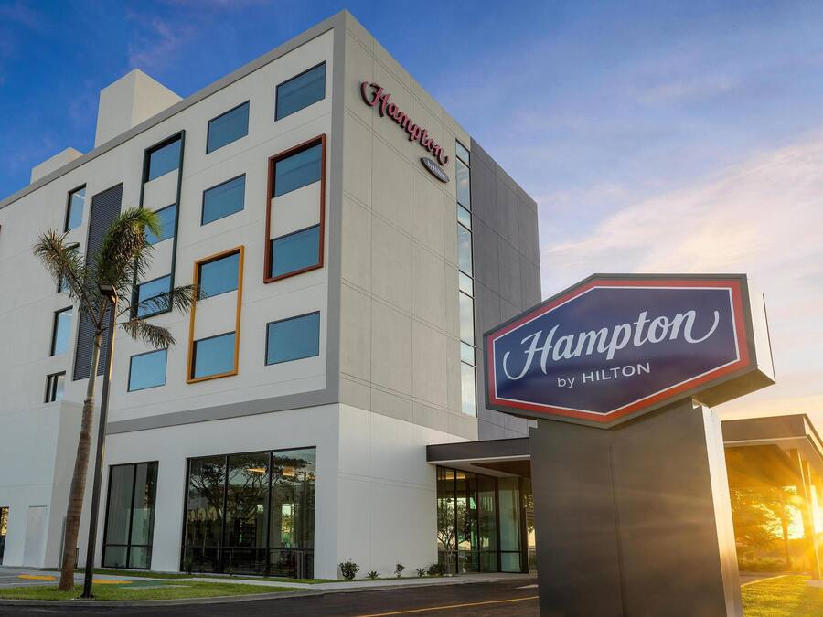 A Hampton by Hilton hotel building with a modern design, large windows, and a prominent sign.