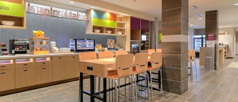 Ein modernes Restaurant mit einer langen Theke, verschiedenen Sitzbereichen und einer Auswahl an Speisen und Getränken.