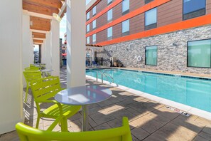 A poolside area with a pool, bright yellow chairs, and a stone wall. - Home2 Suites By Hilton Alcoa Knoxville Airport (Alcoa)