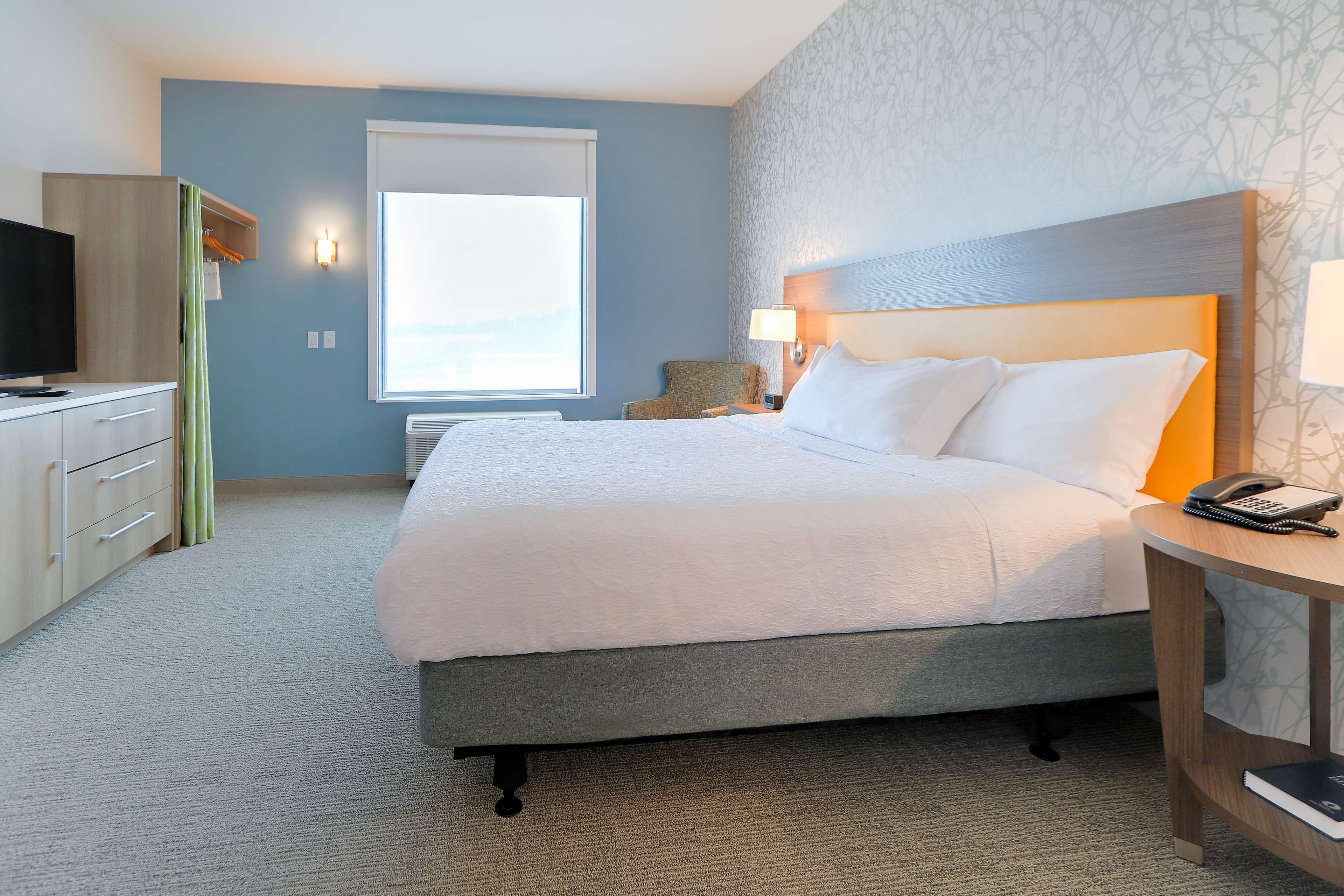 Une chambre d’hôtel avec un lit, un bureau, une chaise et un téléviseur.