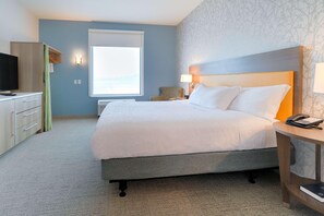 Una habitación de hotel con una cama, un escritorio, una silla y un televisor.