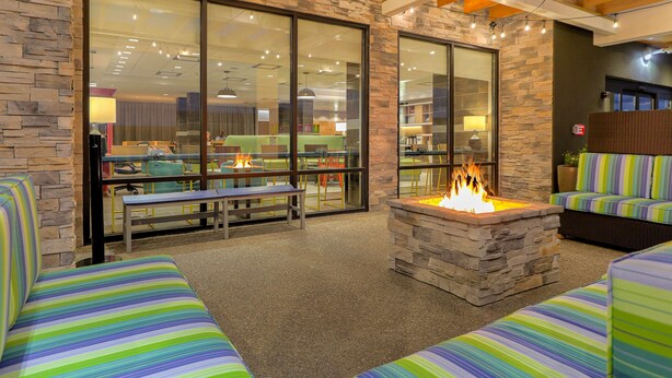 A cozy outdoor seating area with stone walls, a fire pit, and striped cushions.