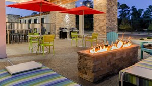 Un patio al aire libre con una chimenea, sombrillas rojas y mobiliario exterior.